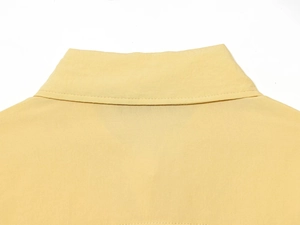 Detail of a bright yellow poplin shirt collar showing fine fabric texture and stitching