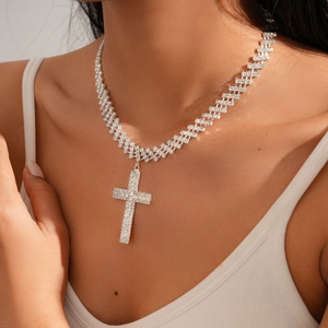 Gros plan du collier avec pendentif en croix argentée et strass brillants sur modèle
