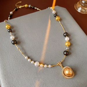 Detailed close-up of a pearl necklace with a gold zircon pendant on a grey velvet stand
