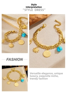 Detail of gold double-layer bracelet with heart, sun and coin charms on stone background