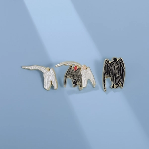 Enamel angel pins set in black and white wings design on light blue background