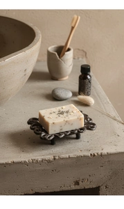 Detail of vintage hollowed cast iron soap dish with natural handmade soap on stone surface