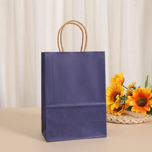 Detail of dark purple paper gift bag with twisted rope handles in a warm lifestyle setting