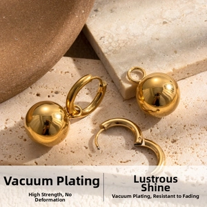 Detail of gold ball drop earrings with polished finish on natural stone background