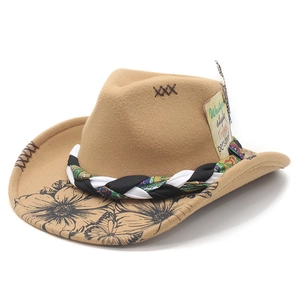 Detail of khaki felt cowboy hat featuring floral patterns, braided band and feather accent