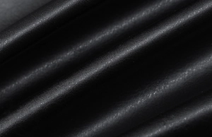 Vista macro del tessuto in pelle nera con texture fine e pieghe naturali del capo