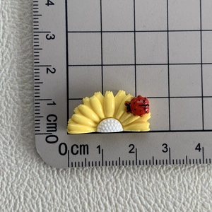 Détail d'accessoire tournesol en résine de 2,5 cm avec coccinelle sur tapis gradué