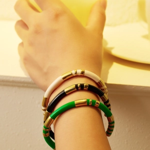 Three-piece stackable enamel bangles in cream, black, and green with gold-tone segments