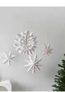 Hanging white paper Christmas star pendants with intricate cutouts and LED light effect