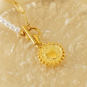 Gold stainless steel pearl necklace with coin pendant and OT toggle clasp on textured tray