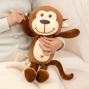 Plush brown monkey doll with expressive face and soft fur held in a cozy home setting