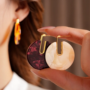 Close-up of vintage tortoiseshell round earrings with gold plated metal hooks on ear