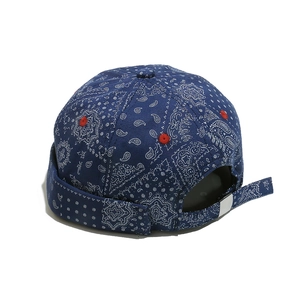 Detail of navy blue paisley docker cap featuring red eyelets and adjustable metal buckle