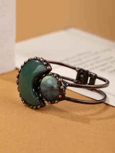 Detailed macro view of bronze moon bracelet with green gemstone and round labradorite