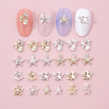 Macro detail of gold and silver star, moon, and shell alloy charms for DIY nail art design