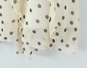 Nahaufnahme von beigem Chiffonstoff mit Punkten, Rüschensaum und plissierten Details