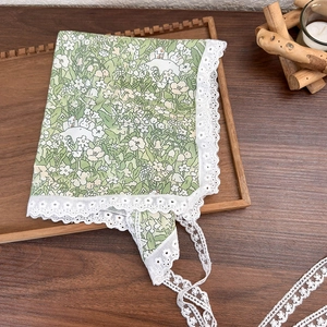 Detailed shot of green floral fabric with white lace edge on a wooden tray
