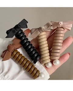 Détail d'élastiques spirales avec nœuds en tissu et perles en quatre couleurs douces