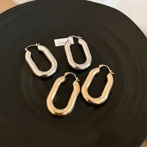 Orecchini a cerchio ovali lucidi in oro e argento esposti su un vassoio nero
