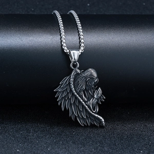 Gros plan du pendentif ange ailé en acier inoxydable argenté avec détails gravés vintage