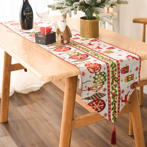 Close-up of knitted Christmas table runner with reindeer patterns and red tassels