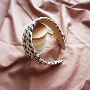 Close-up of a woven raffia headband in beige and black on a wooden candle jar