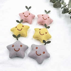 Close-up of star-shaped plush pins with embroidered smiles and green leaf detail