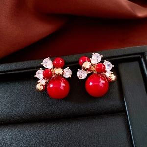 Close-up of 18K gold plated horse-themed red pearl stud earrings on a luxury display box