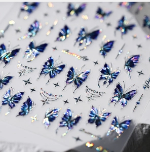 Macro detail of holographic butterfly and star nail art stickers with metallic blue finish