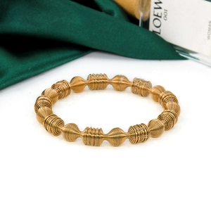 Detail of golden steel spring bracelet on green silk with perfume bottle background