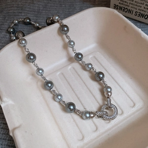Macro detail of grey pearl necklace with silver textured beads and crystal buckle