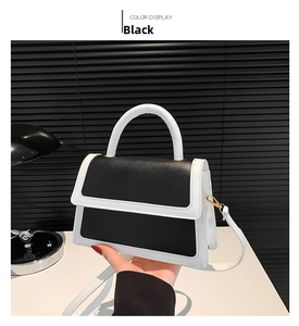 Detail of contrast color handbag with black body, white handle and gold hardware detail