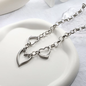 Minimalist silver necklace featuring three hollow heart pendants in polished stainless steel