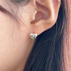 Minimalist 925 sterling silver heart stud earrings with cubic zirconia on a model's ear