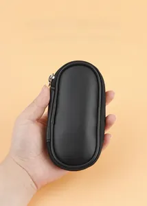 Handheld view of a sleek black matte leather travel makeup brush pouch with a zipper