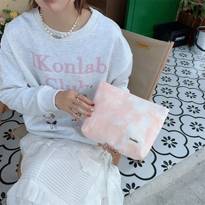 Close-up of pink tie-dye toiletry bag held by a model in an outdoor leisure setting