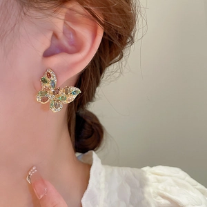 Macro side view of a butterfly earring with colorful zircon stones on a model ear