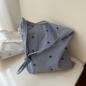 Détail du sac bandoulière en coton à carreaux bleus avec fermeture éclair et étiquette