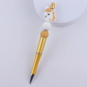 Detail of a golden beaded pen featuring a white and yellow silicone unicorn and rhinestones