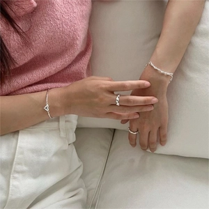 Detail of 925 sterling silver heart rings and textured bracelet on a model
