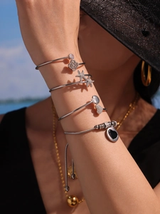 Détail de bracelets superposés en argent avec breloques zircon et étoile de mer
