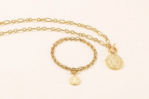 Detail view of gold Saint Benedict medal pendants with T-bar toggles on chain jewelry set