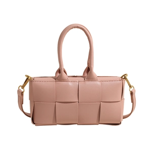 Elegante borsa a mano in pelle intrecciata rosa con tracolla su sfondo bianco