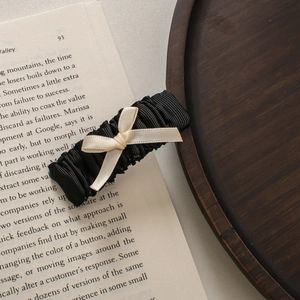 Dettaglio molletta per capelli nera a pieghe con fiocco crema su libro d'epoca