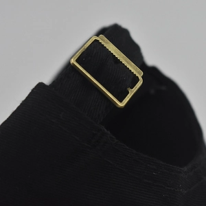 Detailed macro view of the adjustable metal buckle on a black cotton baseball cap