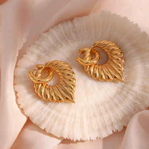 Macro detail of gold leaf pendant earrings with sparkling crystals on silk background