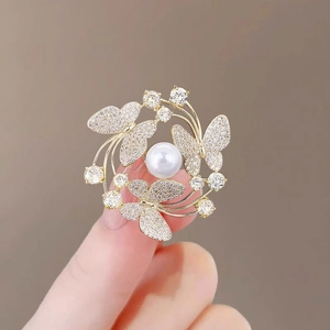 Golden alloy butterfly brooch featuring a center pearl and sparkling zircon stones