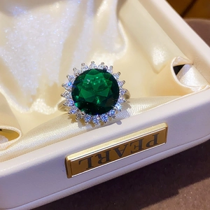 Close-up of a silver ring with an oval green gemstone in a luxury beige jewelry box