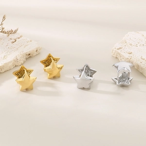 Detailed close-up of gold and silver star-shaped hoop earrings on textured stone