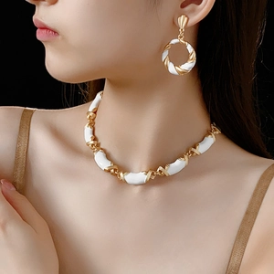 Close-up of vintage gold twist necklace and earrings with white enamel on a model